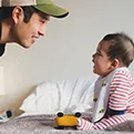 man with hat talking to a baby