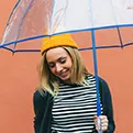 young woman wearing a yellow hat holding an umbrella 